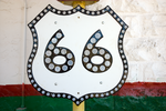black and white vintage route 66 sign in front of a white green and red wall.