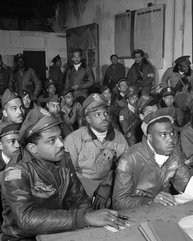 Photograph shows a large group of Tuskegee airmen attending a briefing.