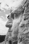 Gutzon Borglum and another men use repeling gear to inspect the carved nose of George Washington at Mount Rushmore in 1932. 