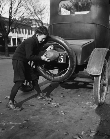 Boy using a spare tire to inflate his footbal in 1924 near Washington DC