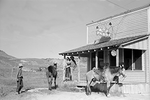 a group of cowboys and horses stand outside a 1920's bar advertising Pabst beer.