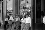 Stockmen in front of the Stockman bar on main street, Miles City, Montana. Other window shows Schlitz Tap Room.