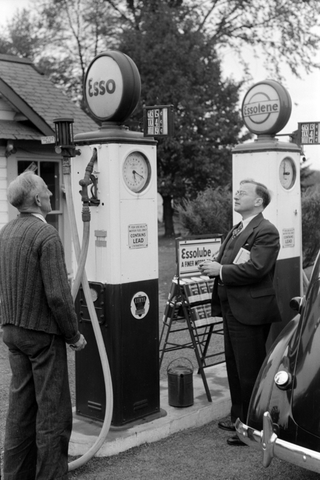 2 men looking at an Esso and Essolene gas pump.