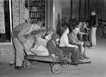 Children with wagons load up groceries for delivery.