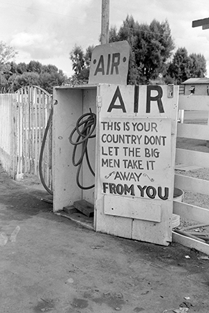 Gas station in Kern County, California. Sign direct motorists to air while another sign says "this is your country don't let the big men take it away from you!"