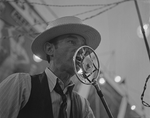 a man at a carnival speaks into a microphone. 