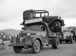 a scrap vehicle sits on the back of a dodge truck with montana license plate 1-x34. A sign on the dodge truck says "salvage for victory".